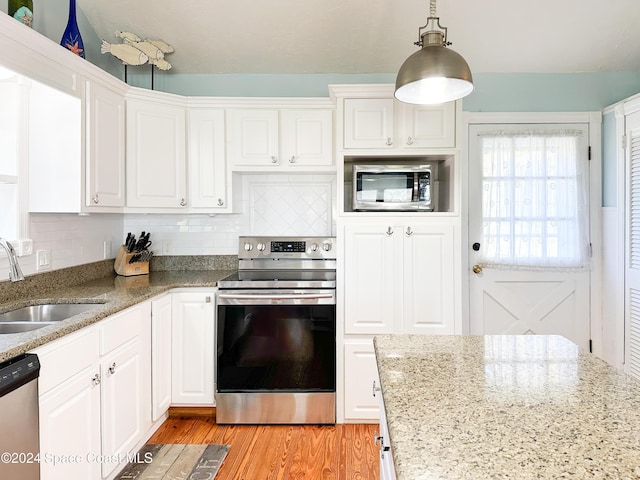 5875 Riverside Dr, Melbourne Beach, FL 32951 - kitchen featuring stainless steel appliances, a sink, white cabinets, light wood finished floors, and tasteful backsplash