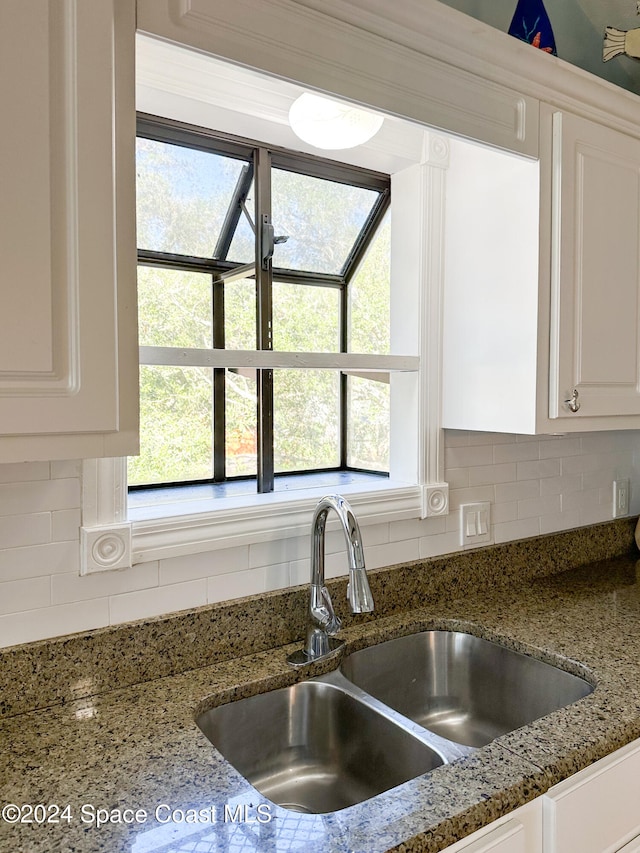 room details with backsplash, stone countertops, white cabinetry, and sink