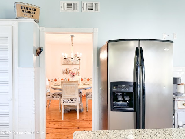 kitchen with stainless steel refrigerator with ice dispenser, an inviting chandelier, hanging light fixtures, and hardwood / wood-style floors