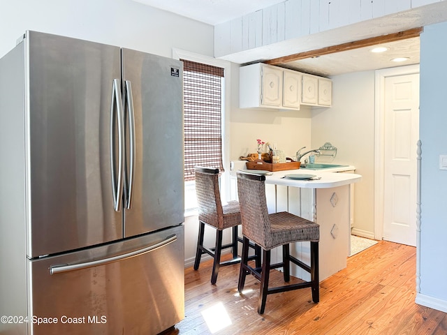 5875 Riverside Dr, Melbourne Beach, FL 32951 - kitchen featuring freestanding refrigerator, light wood-type flooring, a breakfast bar, white cabinets, and a peninsula