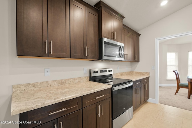 kitchen featuring dark brown cabinetry, light tile patterned floors, stainless steel appliances, and vaulted ceiling