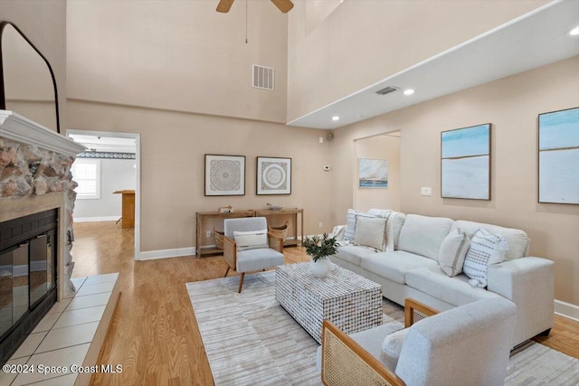 living room with ceiling fan, a fireplace, and light hardwood / wood-style flooring