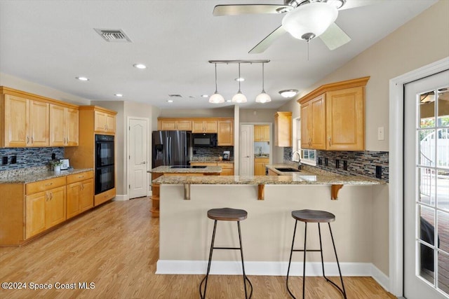 kitchen featuring black appliances, sink, tasteful backsplash, light hardwood / wood-style floors, and kitchen peninsula