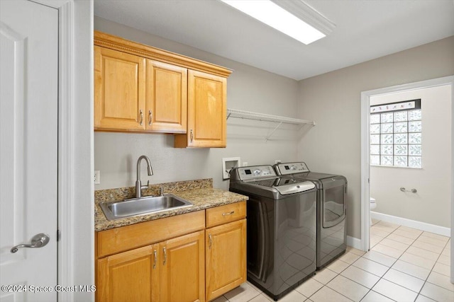 clothes washing area featuring washing machine and clothes dryer, sink, light tile patterned floors, and cabinets