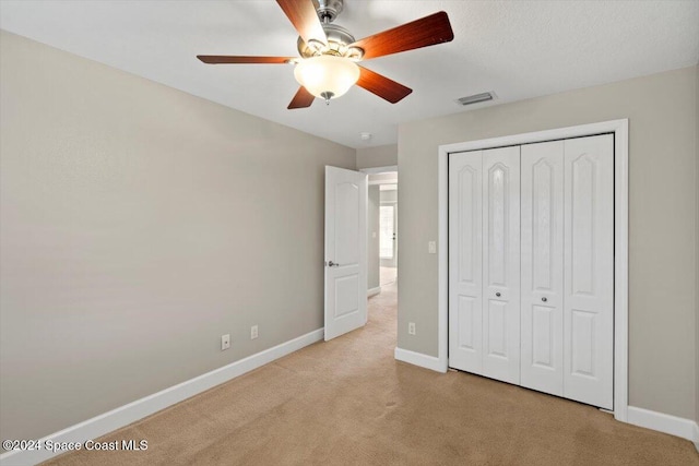 unfurnished bedroom with light carpet, a closet, and ceiling fan