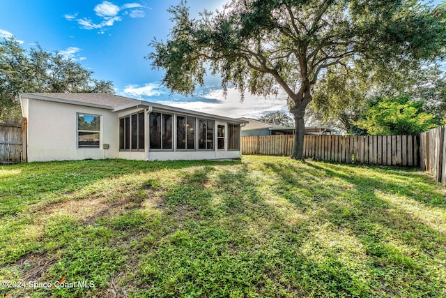 rear view of house with a sunroom and a lawn