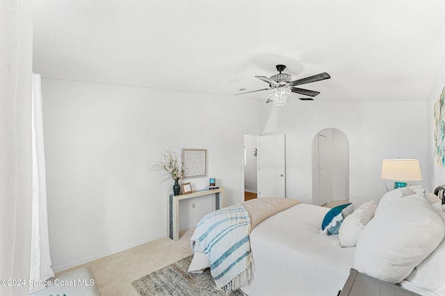 bedroom featuring a textured ceiling, ceiling fan, light carpet, and lofted ceiling