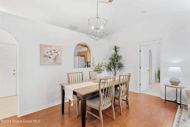 dining space featuring a notable chandelier, lofted ceiling, and light wood-type flooring