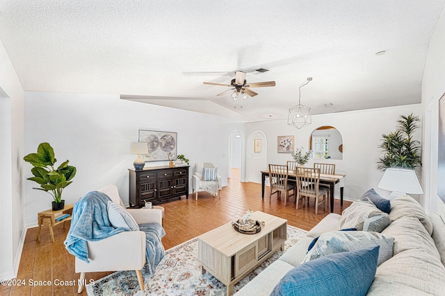 living room with ceiling fan, light wood-type flooring, a textured ceiling, and vaulted ceiling