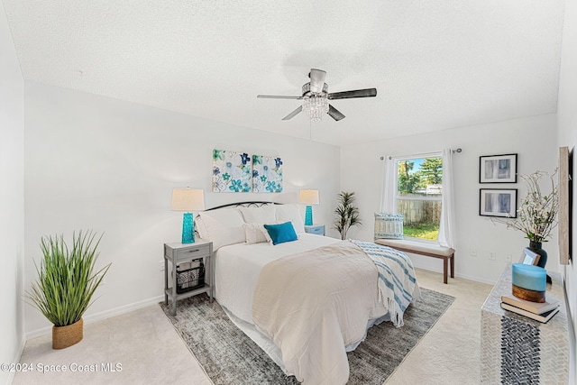 carpeted bedroom with ceiling fan and a textured ceiling