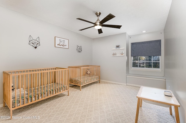 bedroom with carpet floors, a nursery area, and ceiling fan