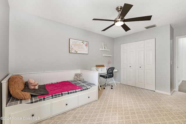 bedroom featuring ceiling fan, light colored carpet, and a closet