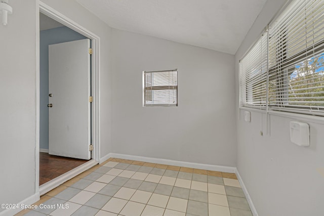 tiled spare room with vaulted ceiling and a healthy amount of sunlight