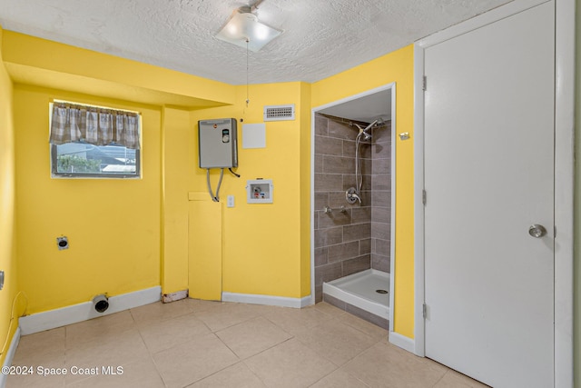 bathroom featuring a tile shower, a textured ceiling, and tile patterned floors