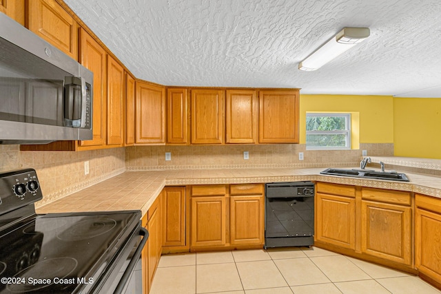 kitchen with light tile patterned floors, sink, backsplash, and black appliances