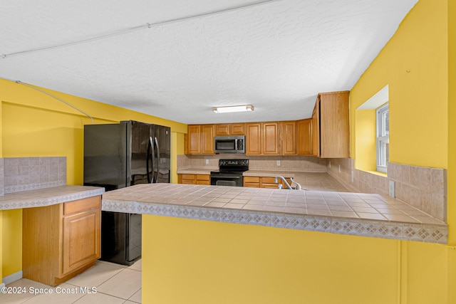 kitchen with kitchen peninsula, light tile patterned floors, backsplash, and black appliances