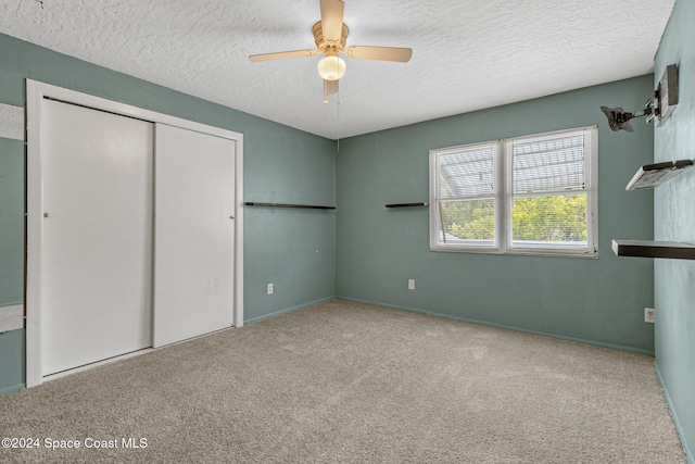 unfurnished bedroom with light carpet, a textured ceiling, a closet, and ceiling fan