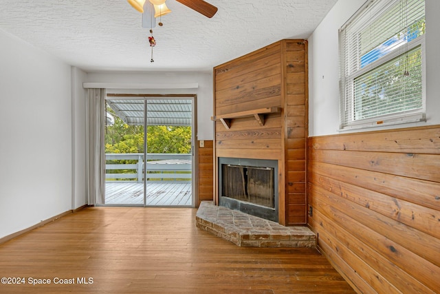 unfurnished living room featuring hardwood / wood-style floors, a textured ceiling, and wooden walls