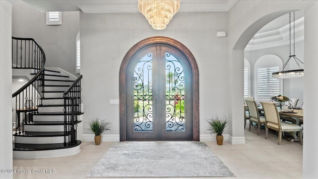 tiled entryway featuring a notable chandelier, ornamental molding, a wealth of natural light, and french doors