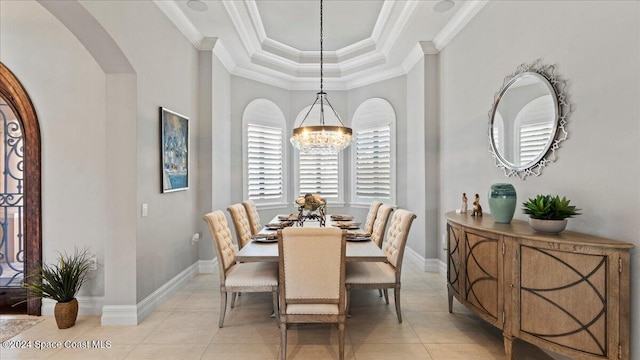 tiled dining space with a notable chandelier, a raised ceiling, and ornamental molding