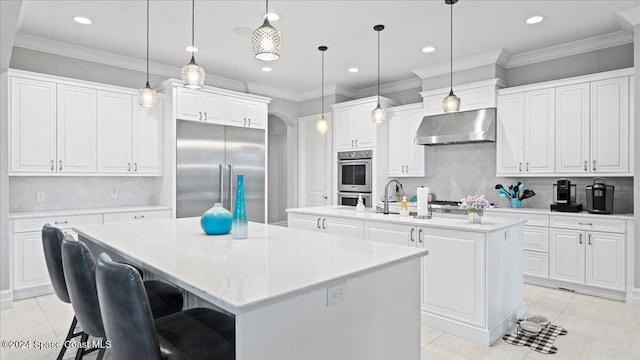 kitchen with pendant lighting, stainless steel appliances, a kitchen island with sink, and wall chimney exhaust hood