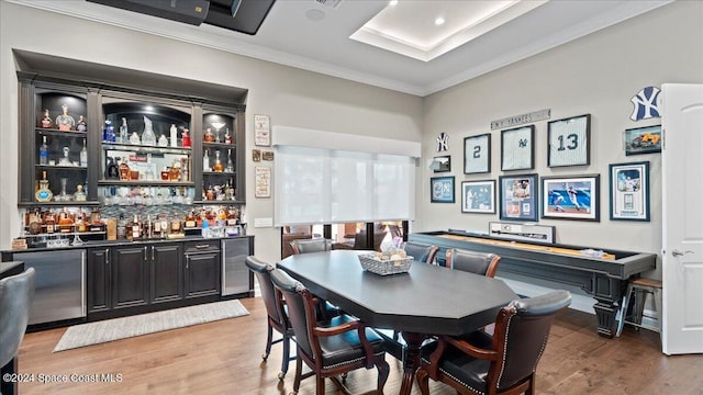 dining room featuring hardwood / wood-style floors, ornamental molding, beverage cooler, and indoor bar