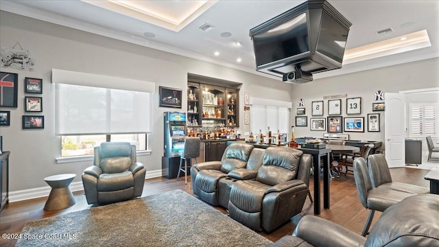 living room featuring a raised ceiling, bar, crown molding, and dark wood-type flooring