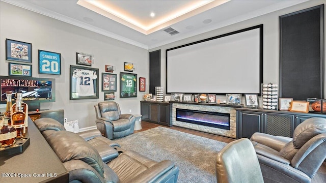 cinema featuring a tray ceiling, crown molding, a fireplace, and hardwood / wood-style floors