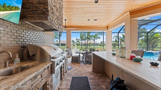 view of patio / terrace featuring a lanai, area for grilling, an outdoor wet bar, and an outdoor kitchen