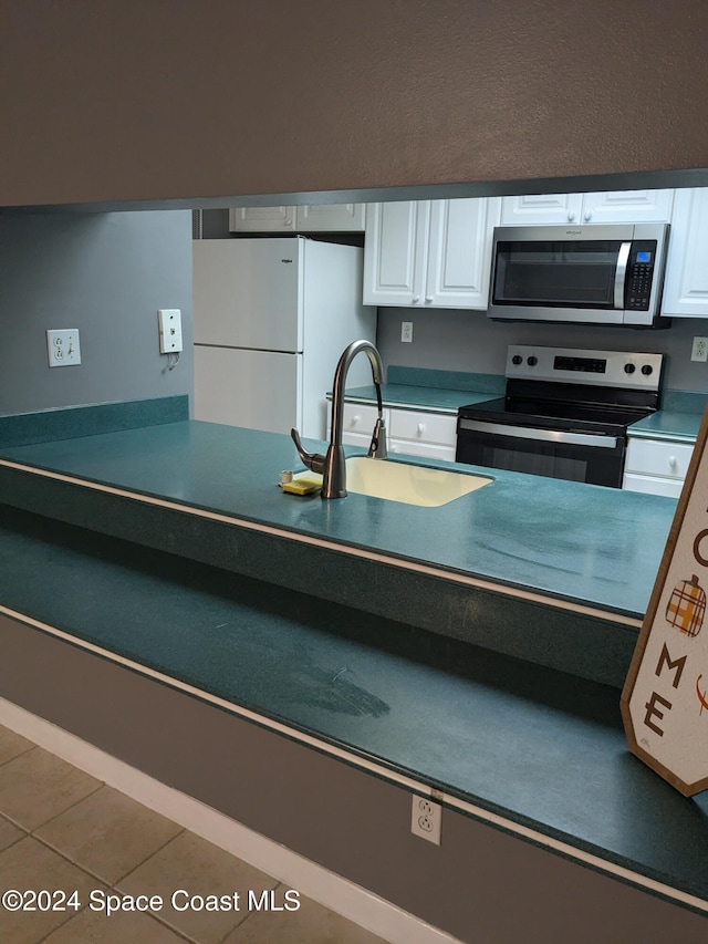 kitchen with white cabinets, stainless steel appliances, tile patterned floors, and sink