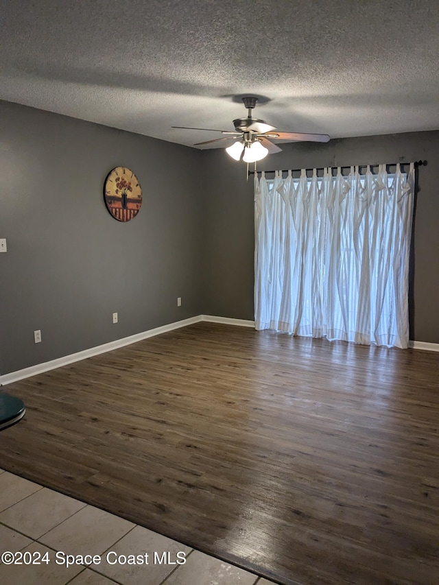 spare room featuring dark hardwood / wood-style floors, ceiling fan, and a textured ceiling