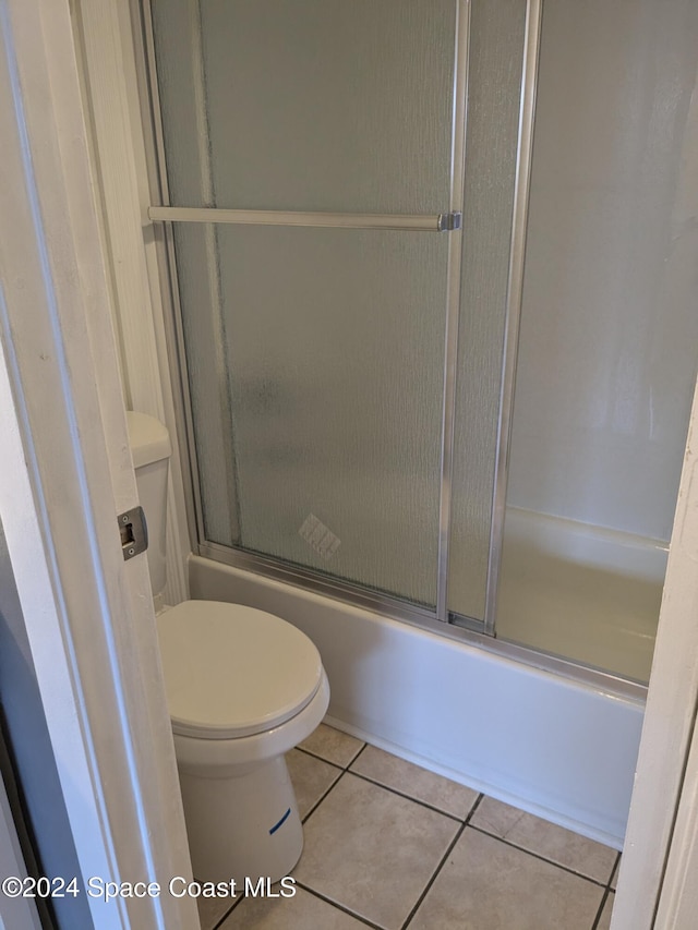 bathroom featuring tile patterned floors, enclosed tub / shower combo, and toilet