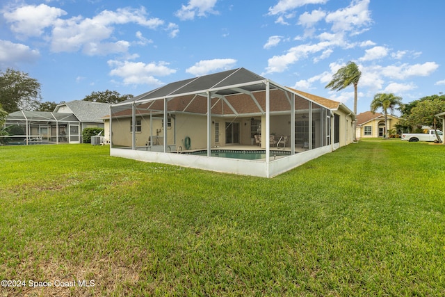 rear view of house with a yard, a lanai, and central air condition unit