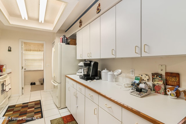 kitchen with white cabinets, white refrigerator, and light tile patterned floors