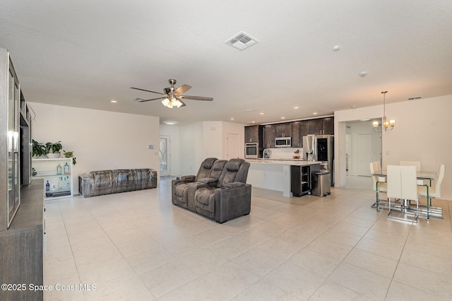 living room with ceiling fan with notable chandelier, sink, a textured ceiling, and light tile patterned floors