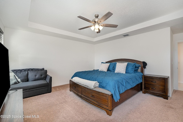 carpeted bedroom with a tray ceiling and ceiling fan