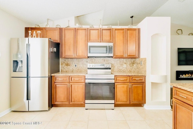 458 Barcelona Rd SE, Palm Bay, FL 32909 - kitchen with stainless steel appliances, vaulted ceiling, decorative backsplash, and brown cabinets