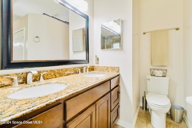 bathroom with toilet, vanity, and tile patterned flooring