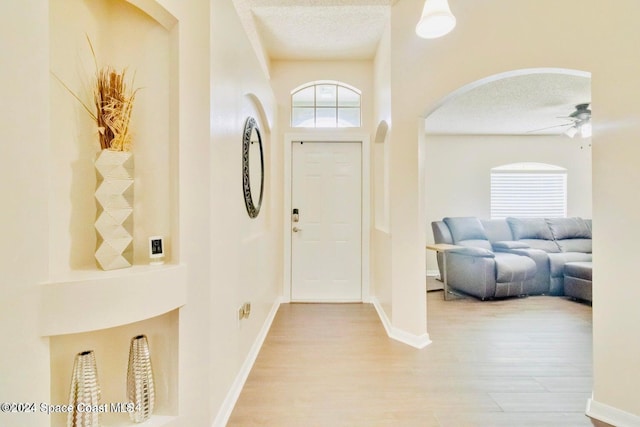 458 Barcelona Rd SE, Palm Bay, FL 32909 - foyer featuring arched walkways, a textured ceiling, a ceiling fan, light wood finished floors, and baseboards