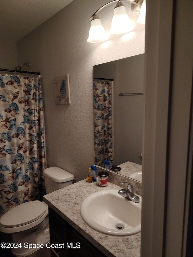 bathroom featuring a shower with shower curtain, vanity, and toilet