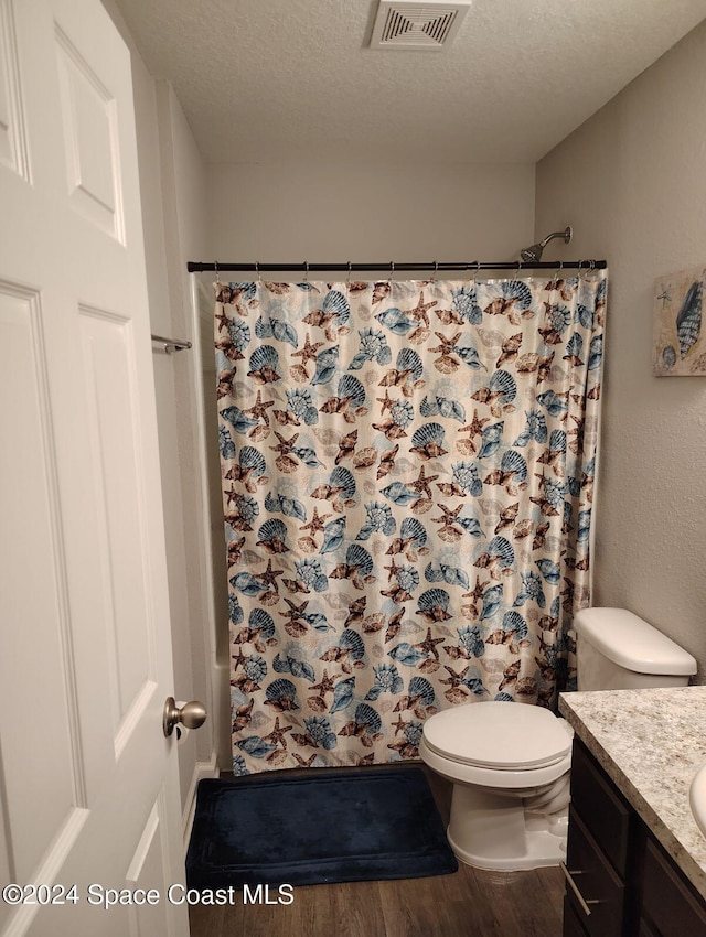 bathroom with hardwood / wood-style floors, vanity, a textured ceiling, and toilet