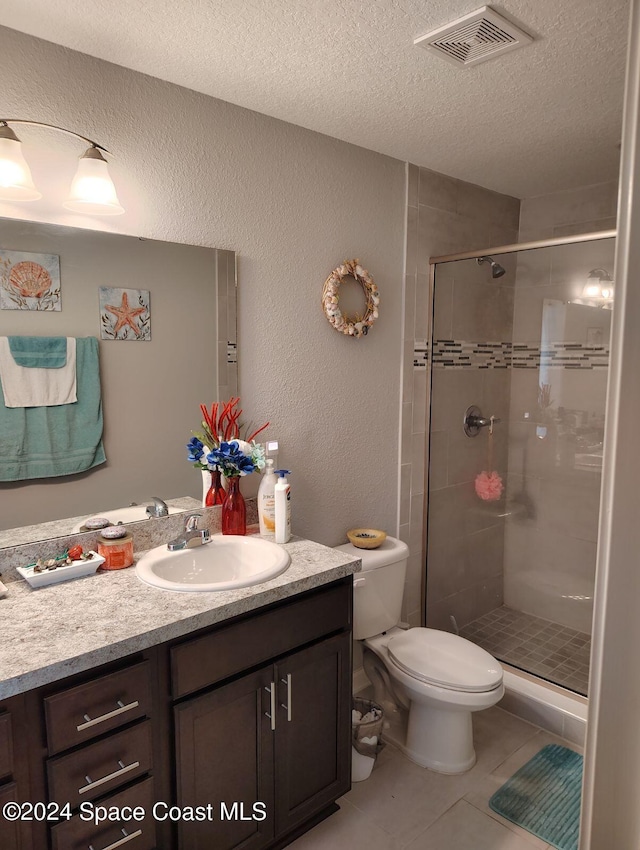 bathroom with tile patterned flooring, an enclosed shower, a textured ceiling, toilet, and vanity