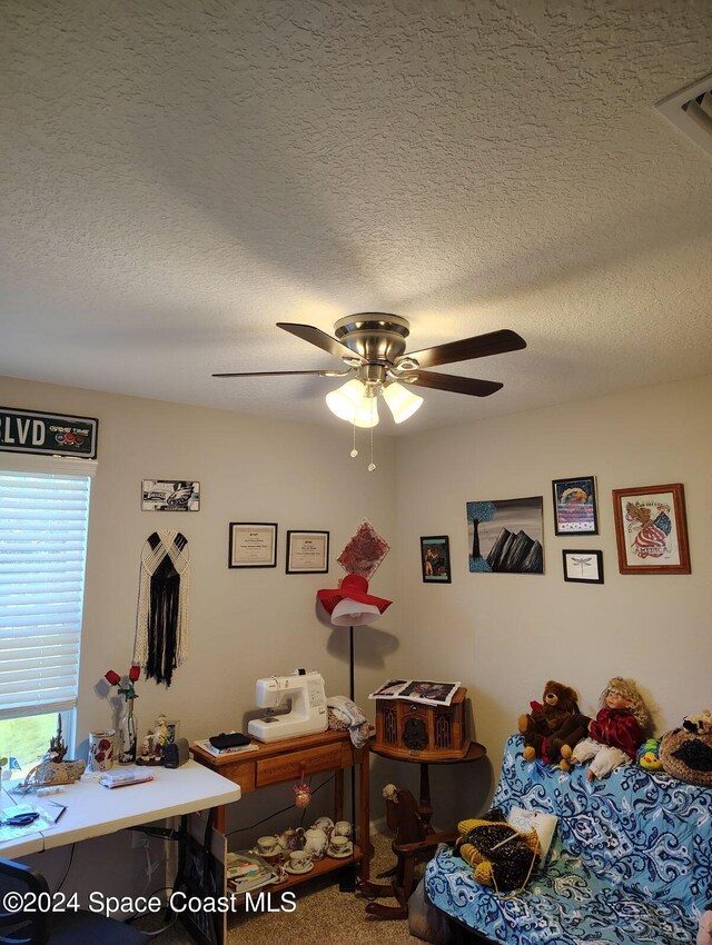 bedroom with ceiling fan, carpet floors, and a textured ceiling