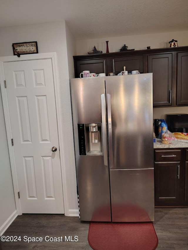 kitchen with dark brown cabinets, dark wood-type flooring, and stainless steel refrigerator with ice dispenser