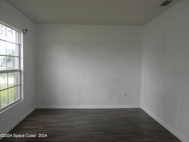 empty room featuring plenty of natural light and dark wood-type flooring