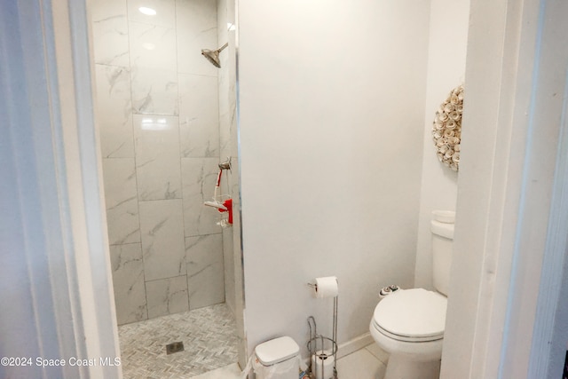 bathroom with tile patterned flooring, a tile shower, and toilet