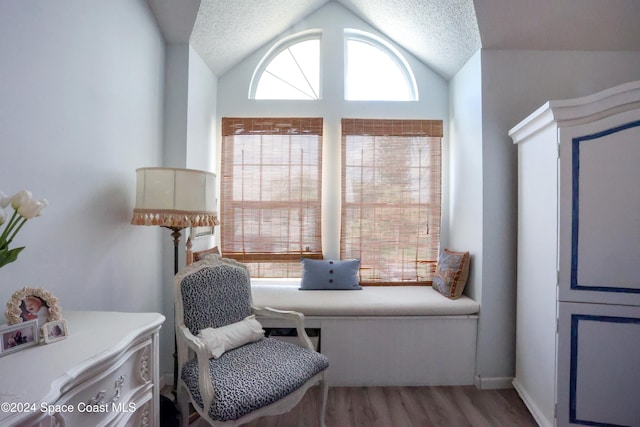 sitting room featuring hardwood / wood-style flooring, a textured ceiling, and vaulted ceiling