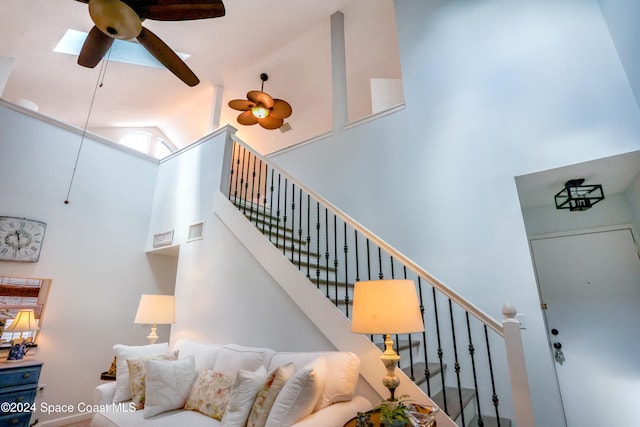 stairs with ceiling fan and high vaulted ceiling