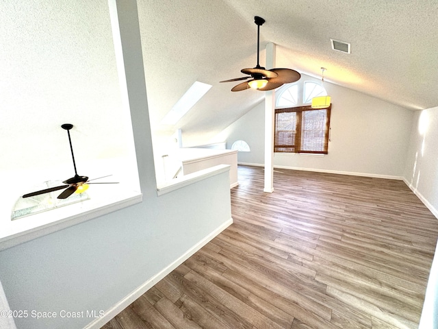 additional living space featuring visible vents, a textured ceiling, baseboards, and wood finished floors