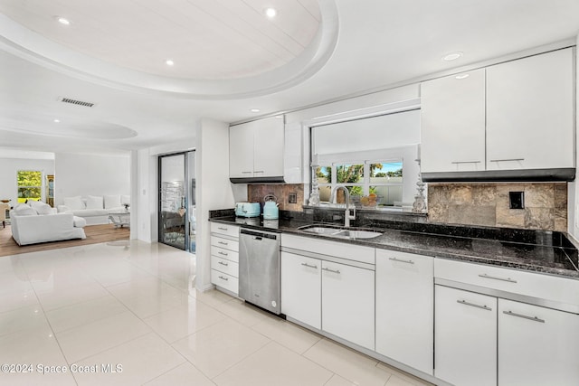 kitchen with backsplash, sink, stainless steel dishwasher, a tray ceiling, and white cabinetry